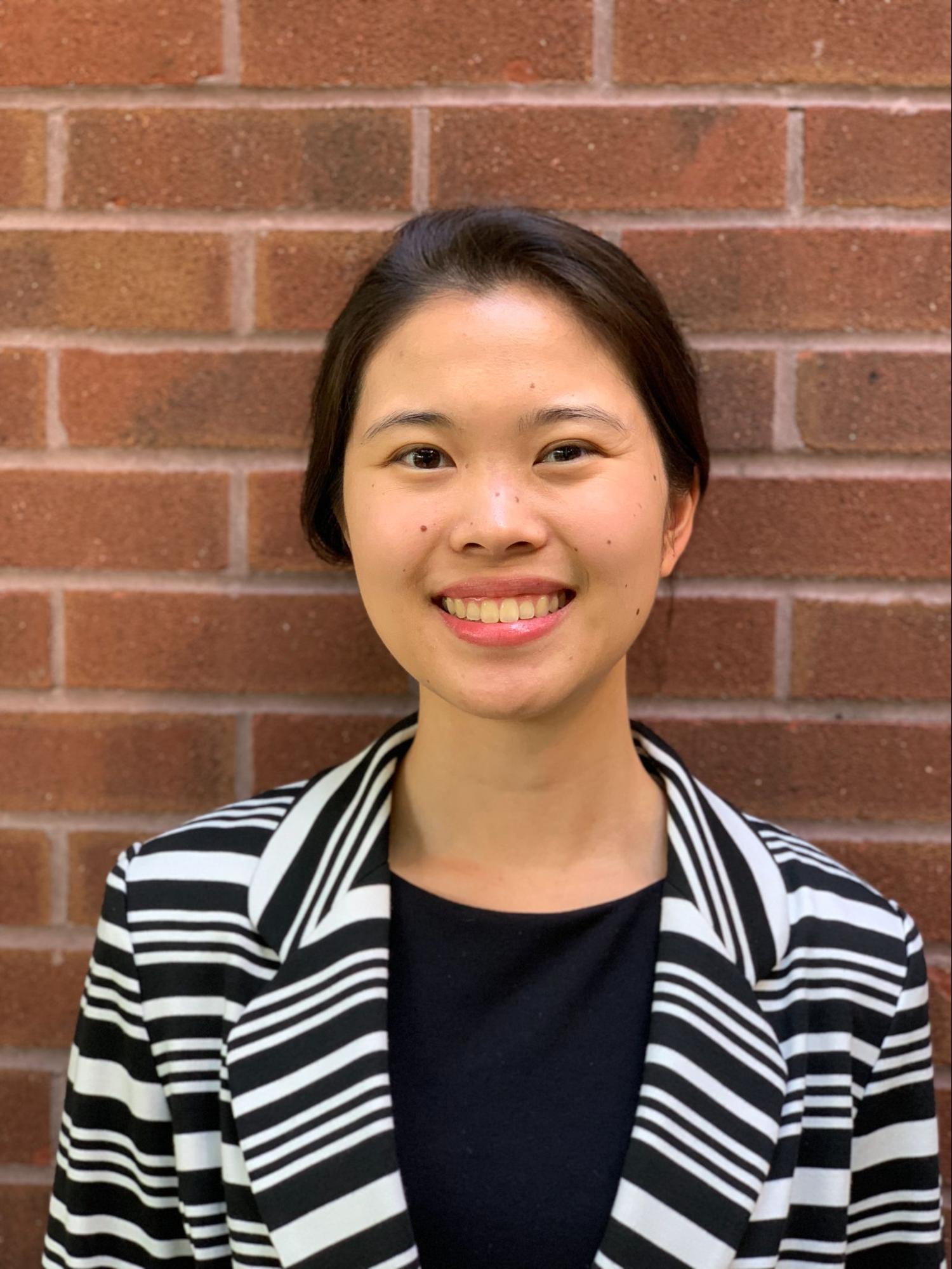 Picture of Amy smiling in front of brick wall. 