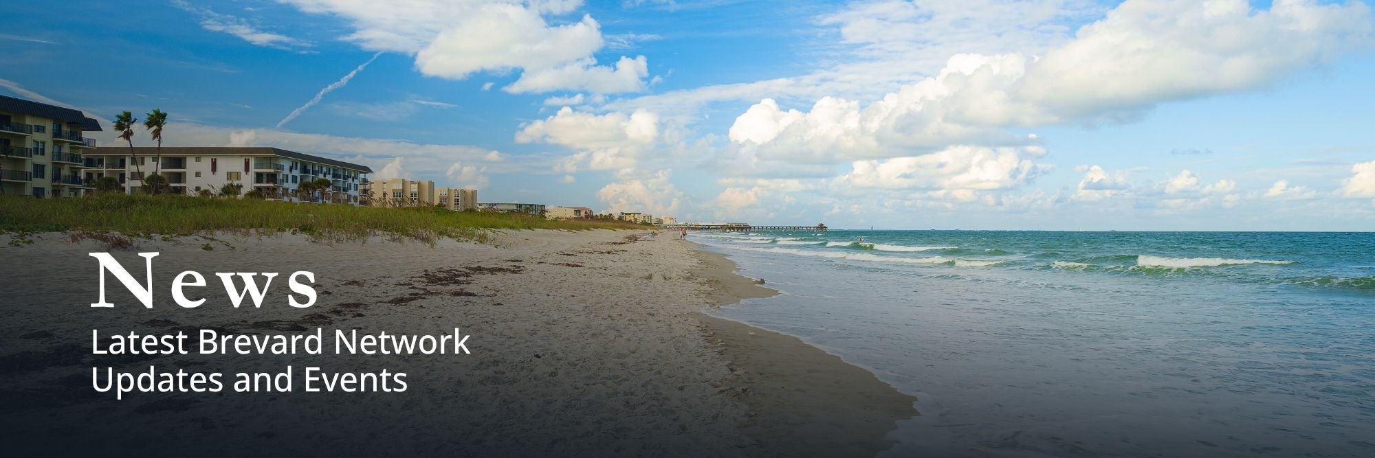 Image of a blue sky and a sandy beach with resort style buildings in the background 